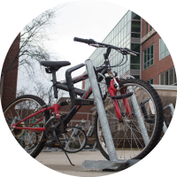 A photo of a red bike parked in a bike rack outside of Brody Hall. 
